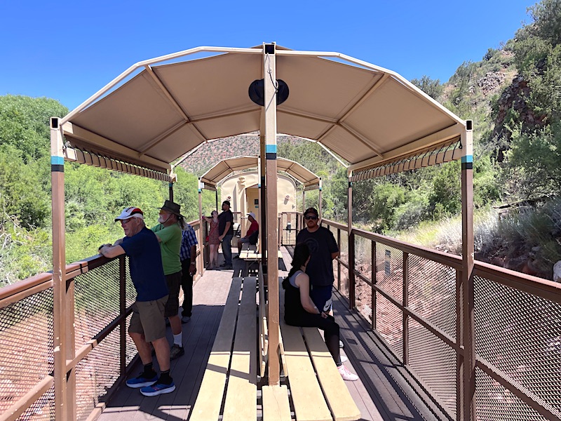 Passengers viewing the scenery from an open-air viewing platform railway car