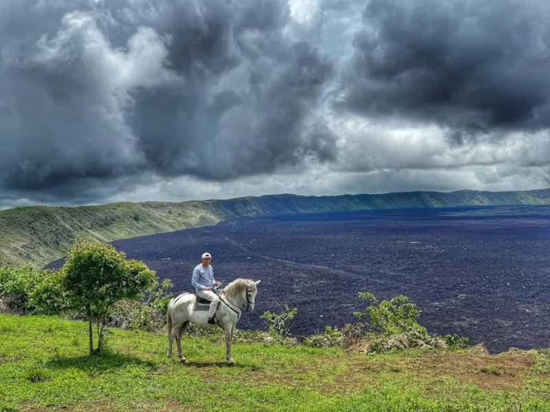 A solitary rider overlooks the Galápagos' largest caldera from the rim of Sierra Negra Volcano, Isabela Island, Galápagos.