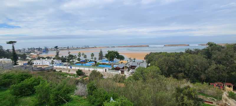 View over a green coastal community, sandy beach and Atlantic Ocean in Morocco.