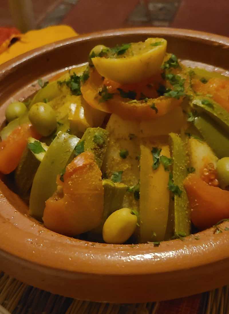 Traditional Moroccan vegetable tagine with potatoes, zucchini, carrots, tomatoes, olives and herbs.